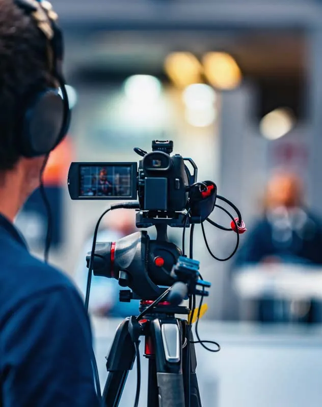 A video camera seen from the back filming a subject