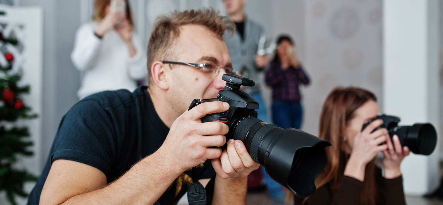 Two photographers in black shirts capturing images at an event