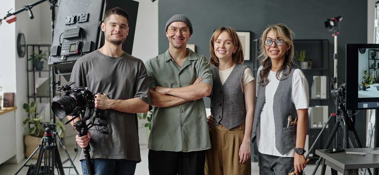 A team of four happy looking video and photography professionals smiling at the camera