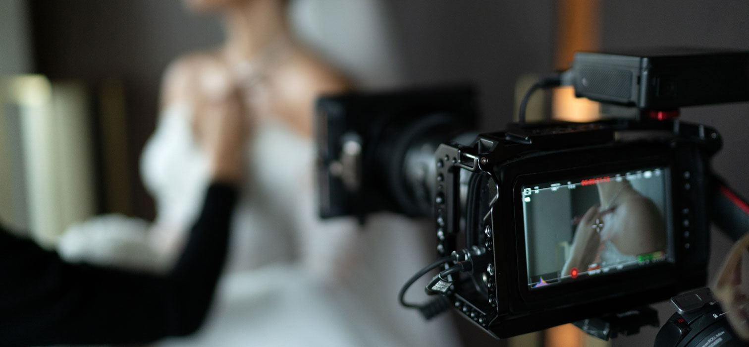 Behind the camera view of a bride getting ready as she is filmed by a wedding videographer