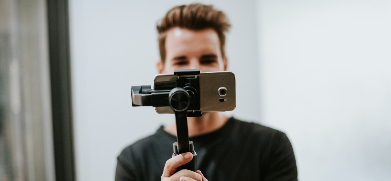 A content creator standing behind a camera filming a female influencer