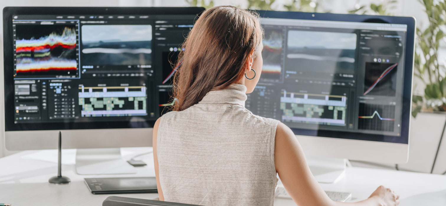 A computer desktop showing two monitors and an Apple keyboard for editing