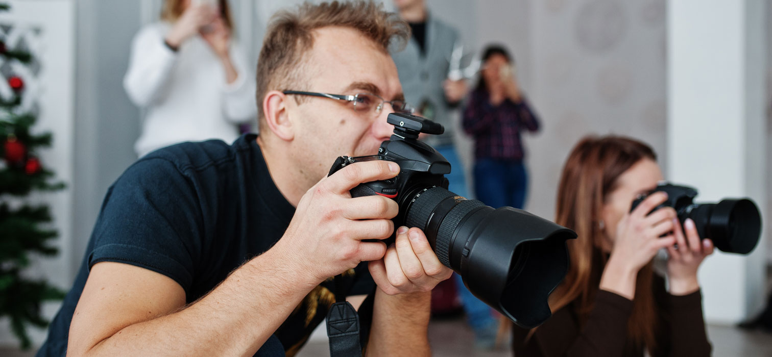Two photographers in black shirts capturing images at an event