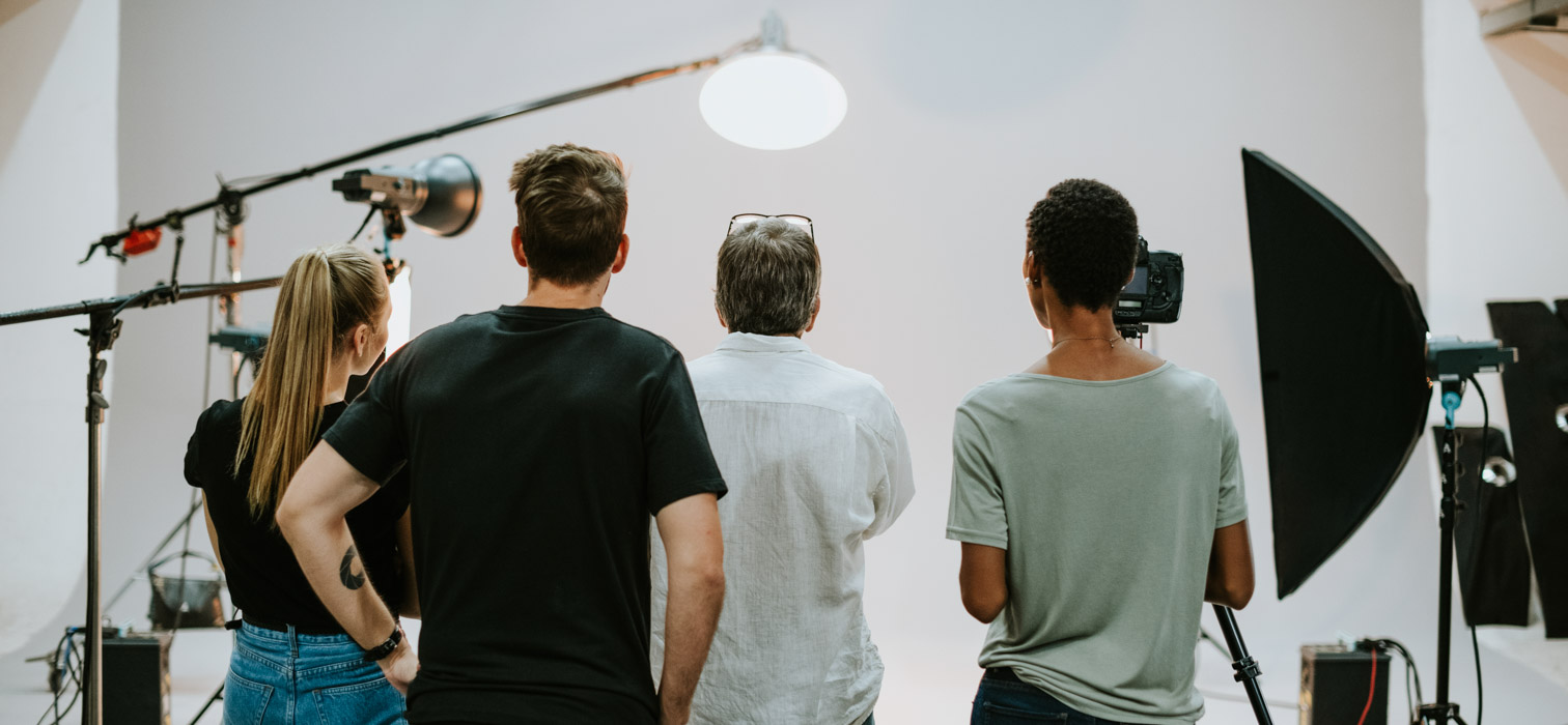 A team of four happy looking video and photography professionals smiling at the camera
