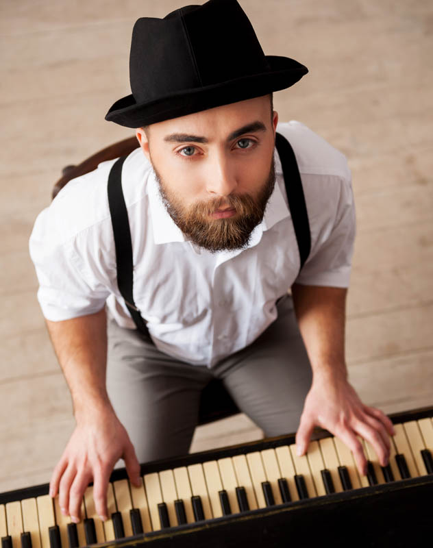 A young man playing on a piano whilst looking up at the camera for a music video