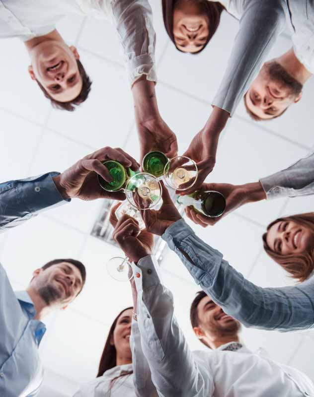A team of staff and colleagues seen from underneath toasting together with glasses