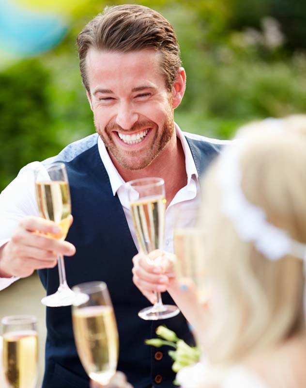 An attractive looking man holding a glass of champagne and toasting friends