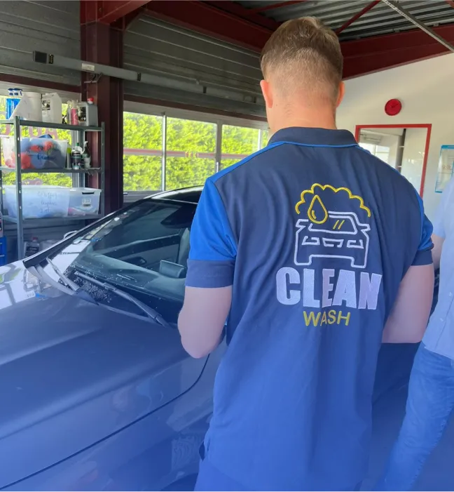 A CleanWashAuto employee wearing a polo shirt with the company logo on it.