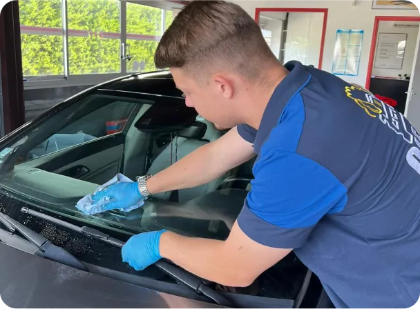 An employee cleaning windshield