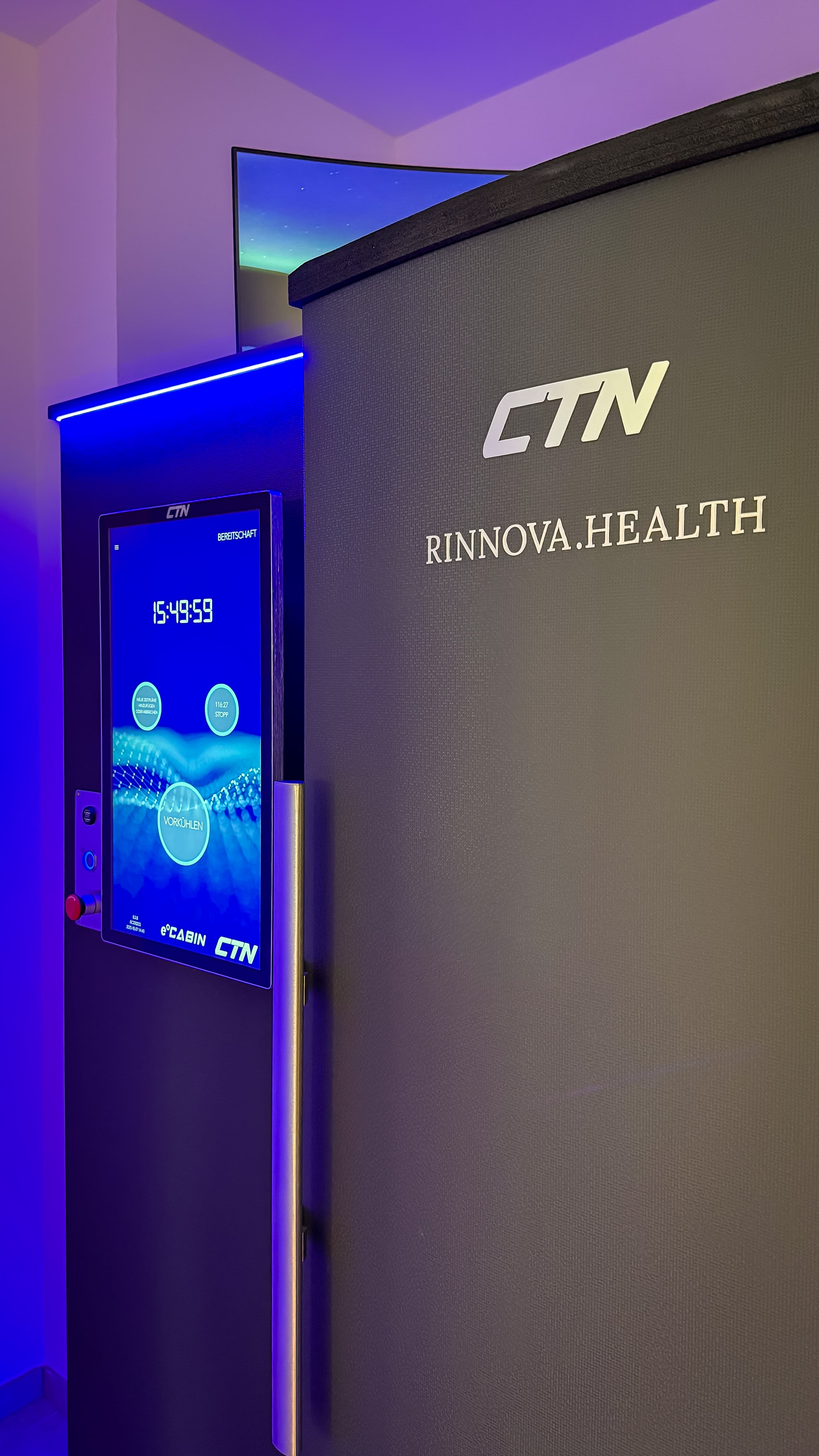 Clear natural pond with plants and a wooden cabin in the background, snow-capped mountains under a blue sky.