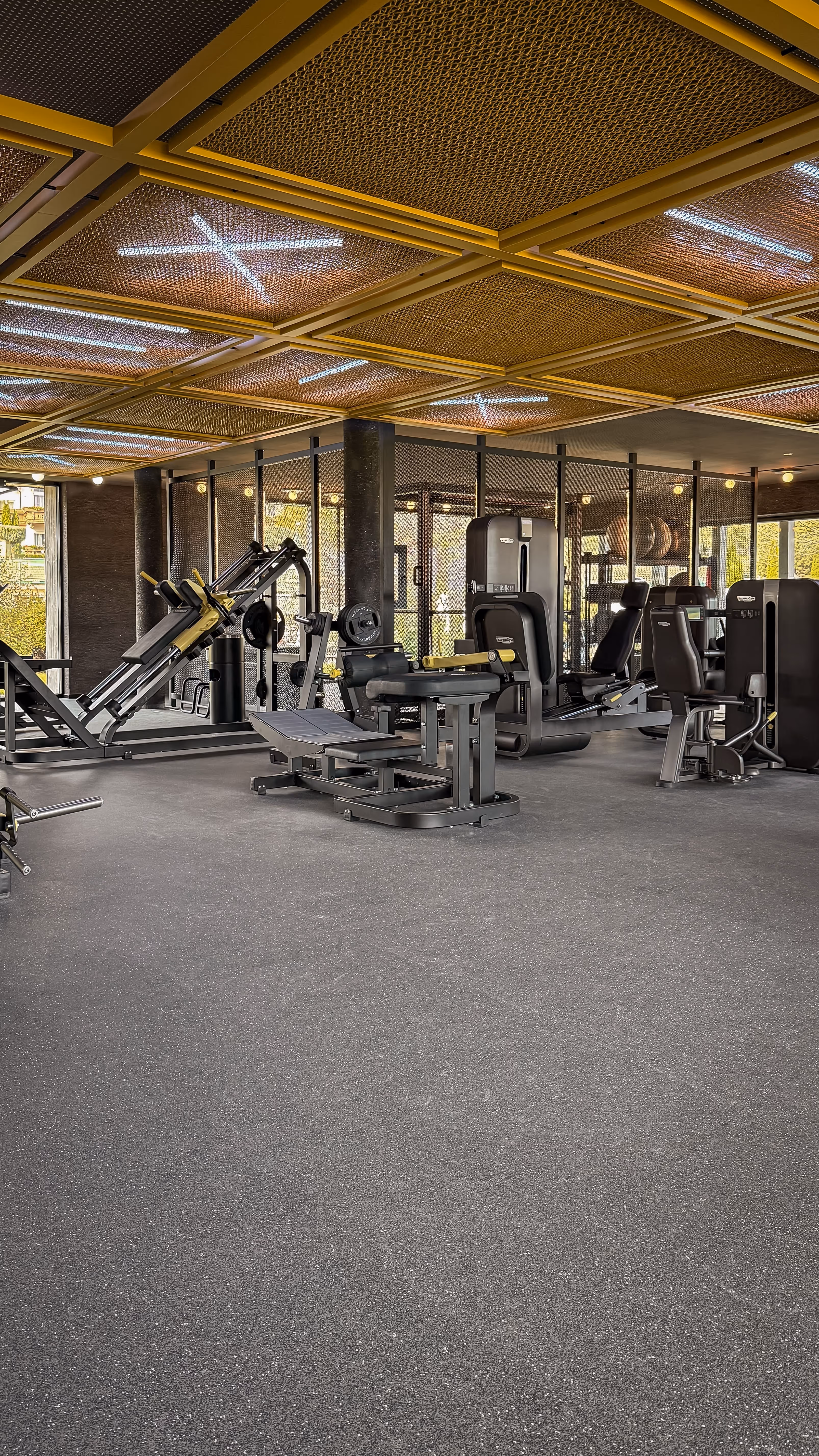 Sunlit sauna interior with wooden benches and folded white towels, with a glass door offering a view of mountains and buildings outside.