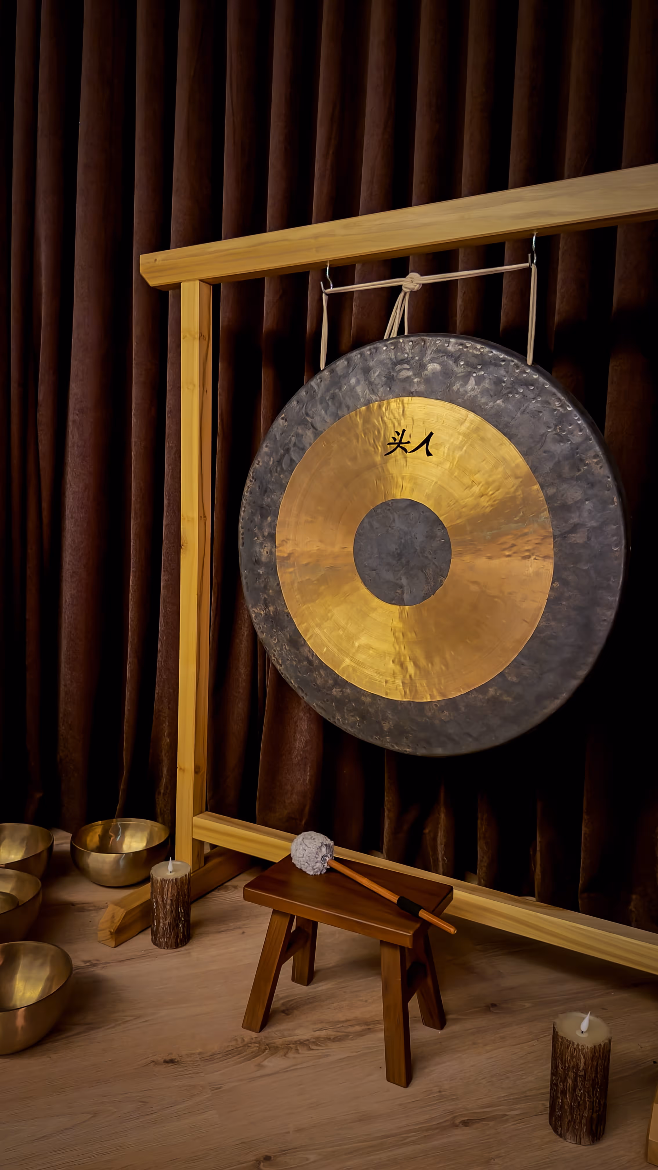 Indoor beige hammock chair with cushions near large glass windows overlooking an outdoor deck with lounge chairs and a mountain landscape.