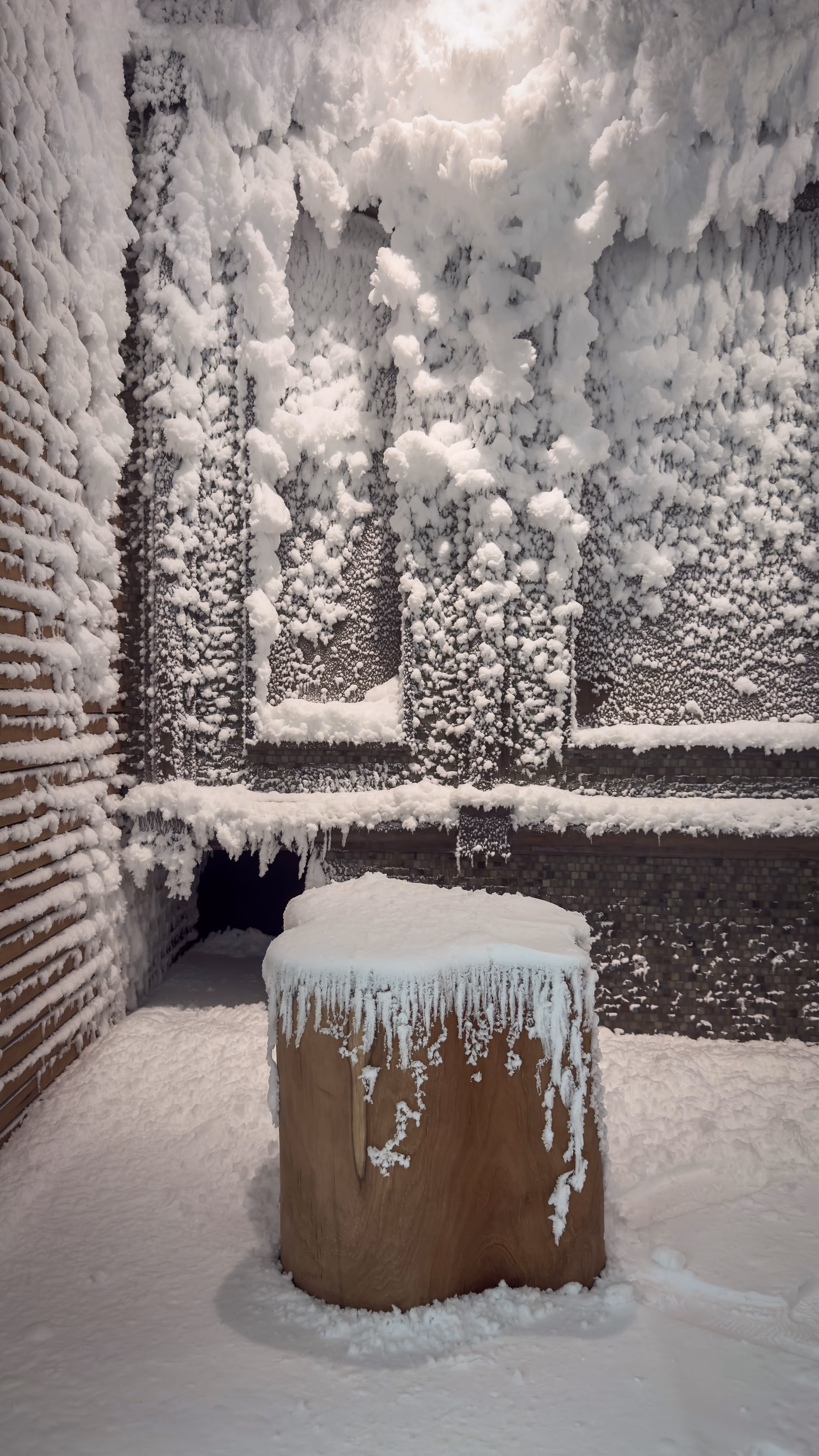 Clear natural swimming pond with lounge chairs and wooden decks, mountains and blue sky in the background.