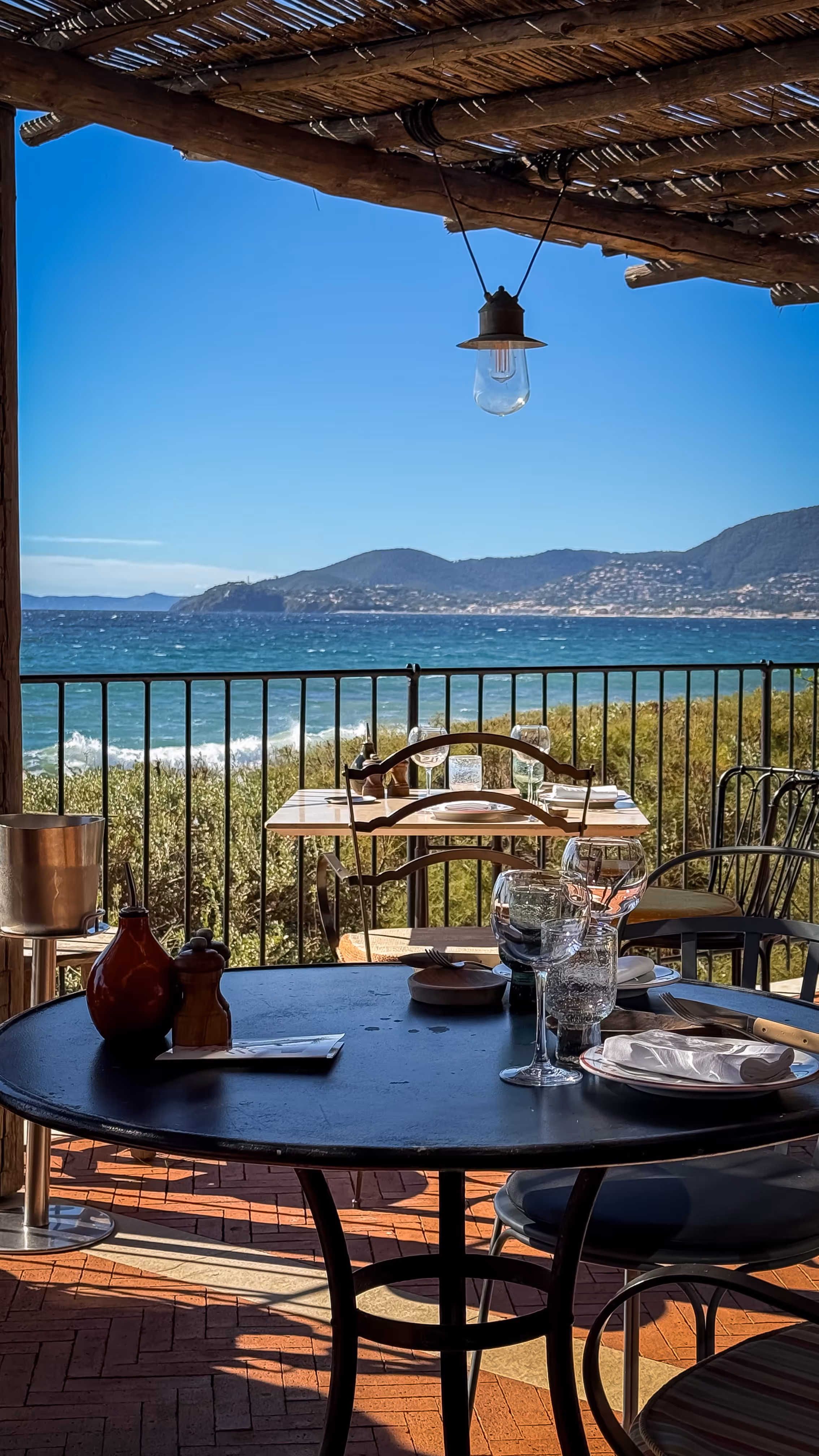 Clear natural swimming pool with lounge chairs and a mountain backdrop under a blue sky.