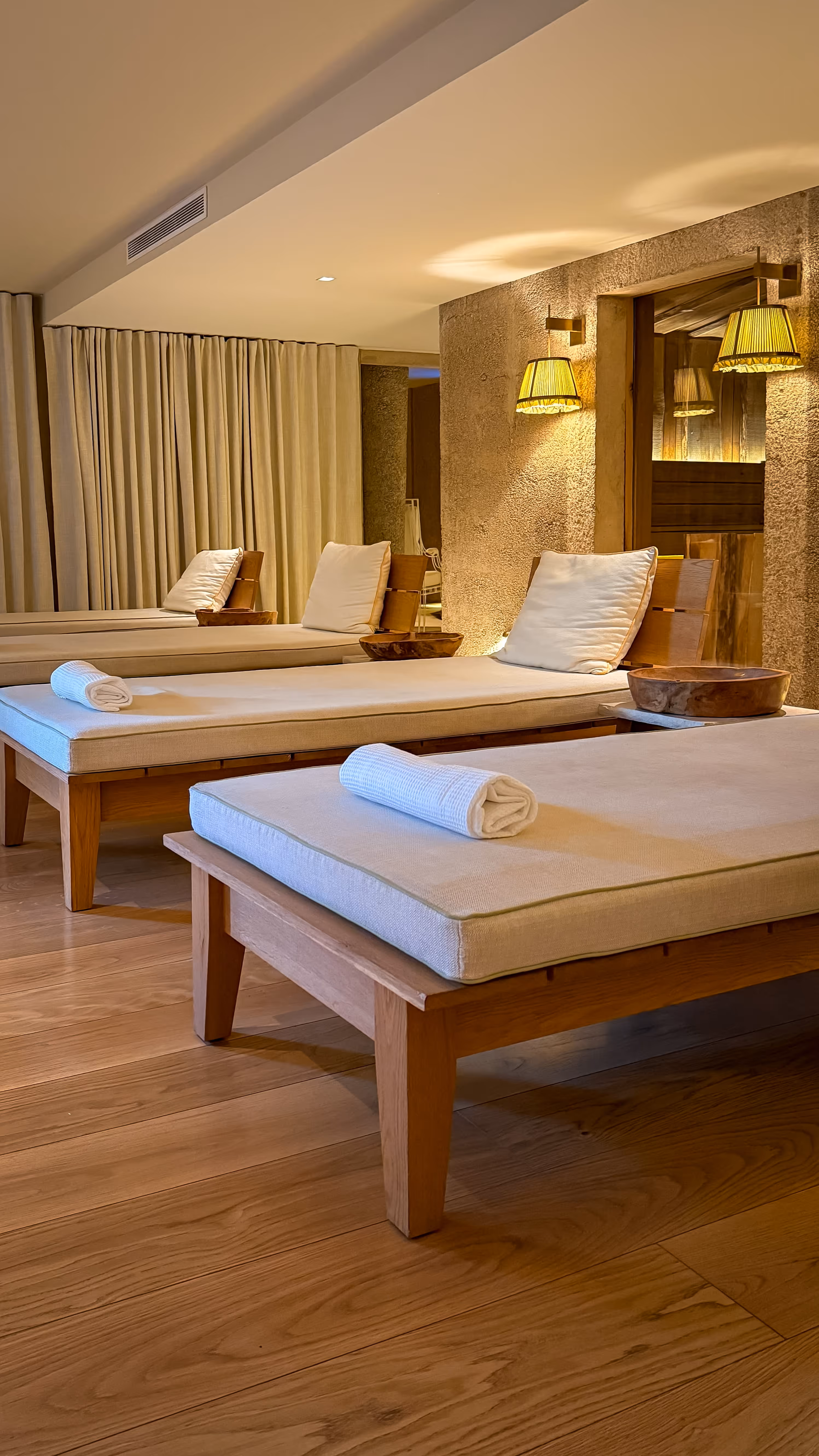 Clear natural swimming pond with lounge chairs and wooden decks, mountains and blue sky in the background.