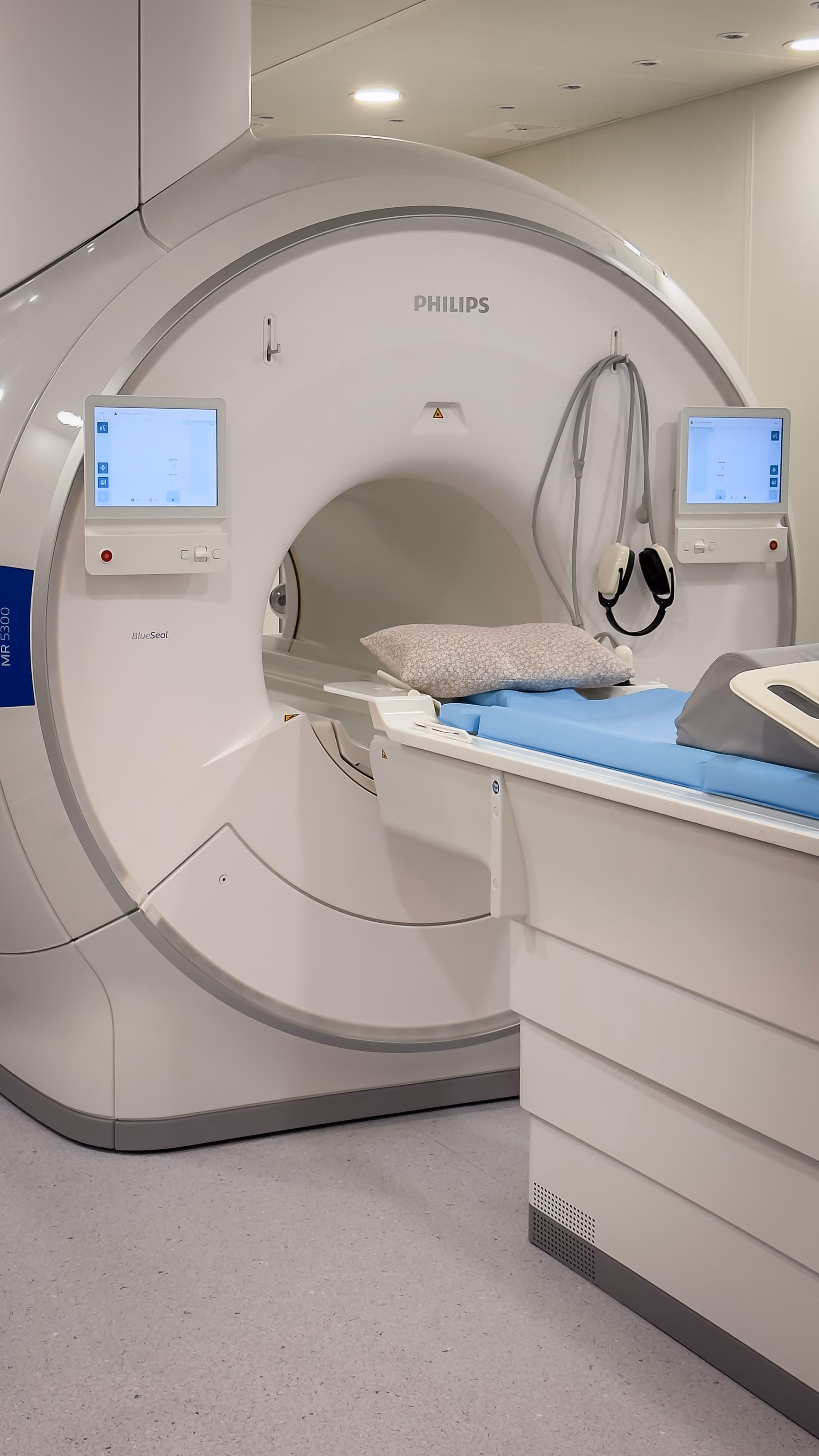 Philips MRI machine with patient table featuring a blue sheet and pillow, inside a clinical room.