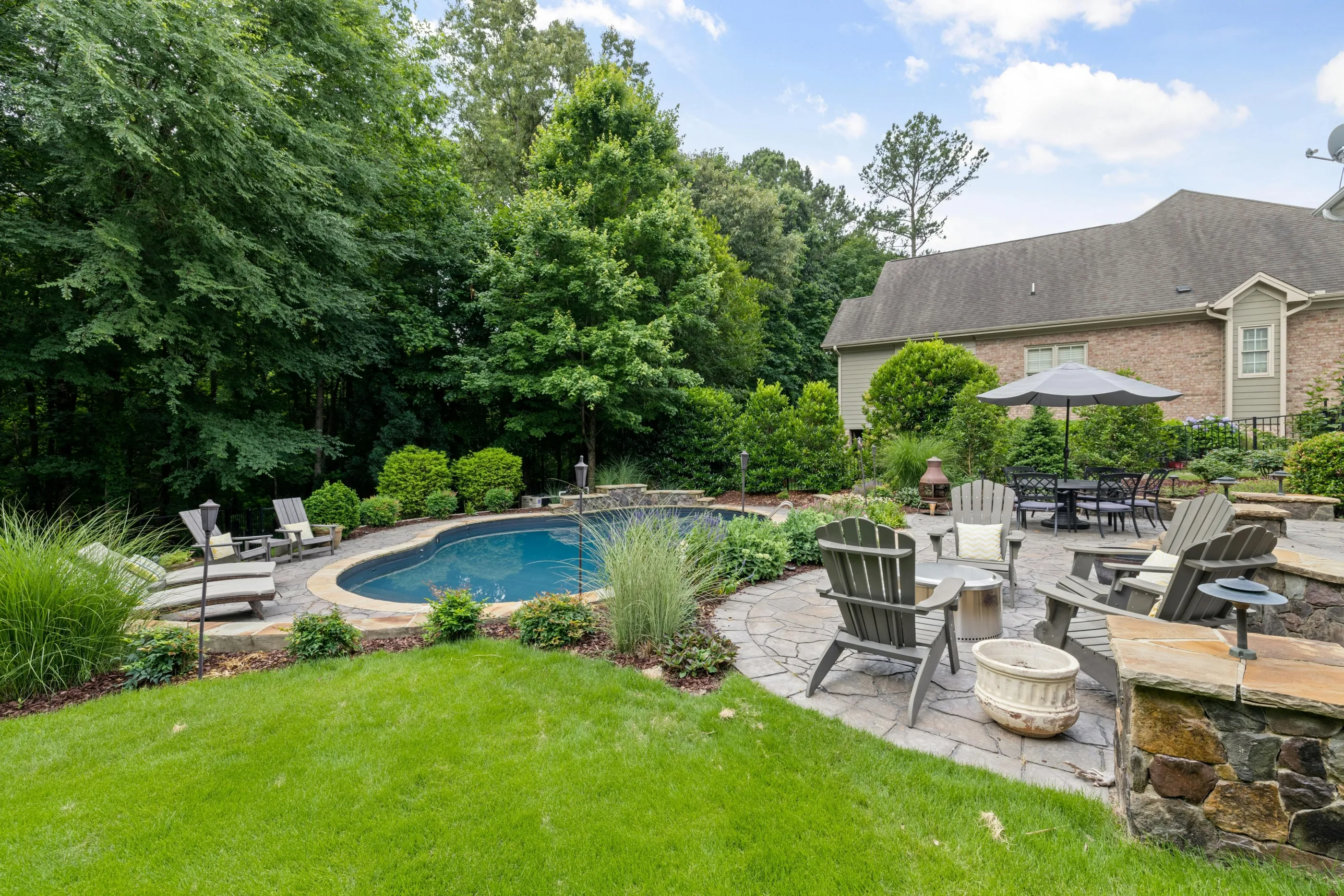 Landscaped backyard with custom swimming pool, paver patio, lawn, and outdoor seating
