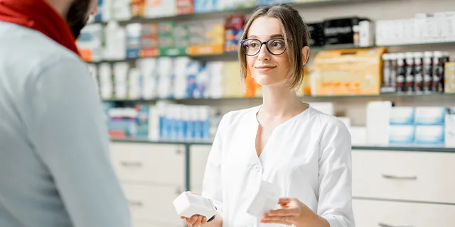 Apoteker presenterer medisin til kunde, illustrerer henting av reseptbelagte medisiner etter digital konsultasjon med Askin.