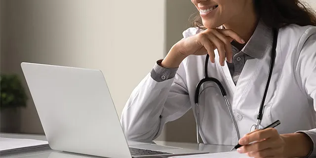 Nærbilde av helsepersonell som arbeider foran pc-skjerm på legekontoret