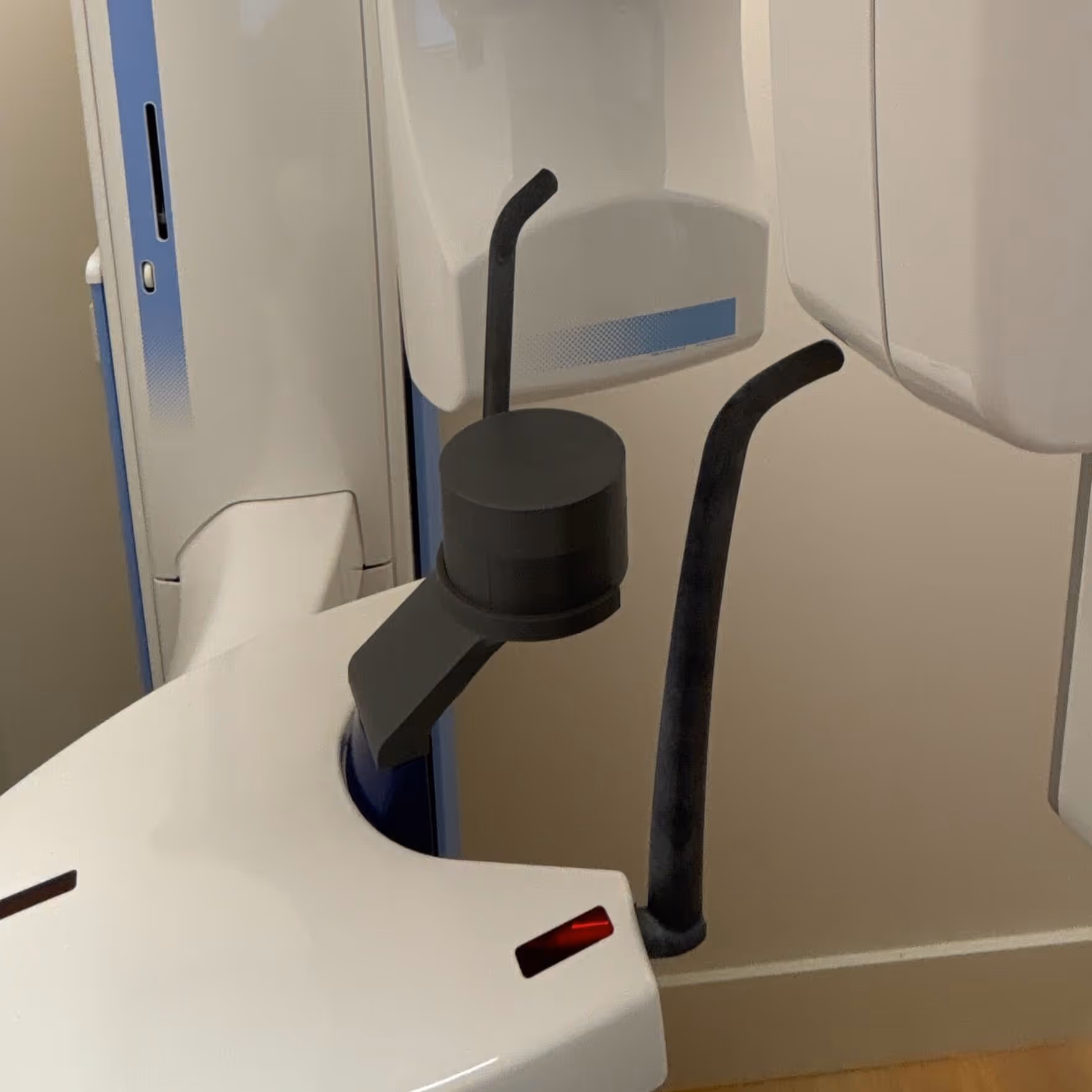 Close-up of a medical imaging machine with a black cylindrical component and surrounding white plastic parts.
