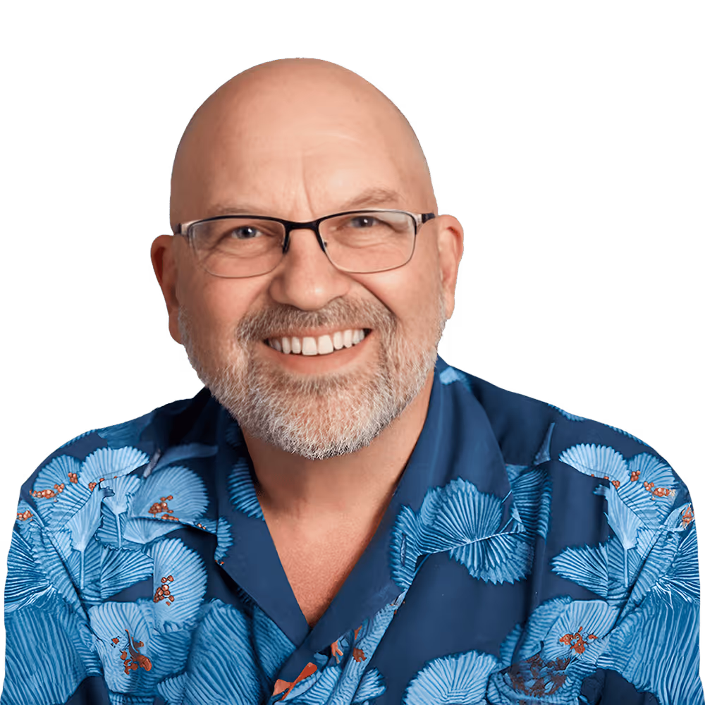 Smiling bald man with glasses and a white beard wearing a blue shirt with a floral pattern.