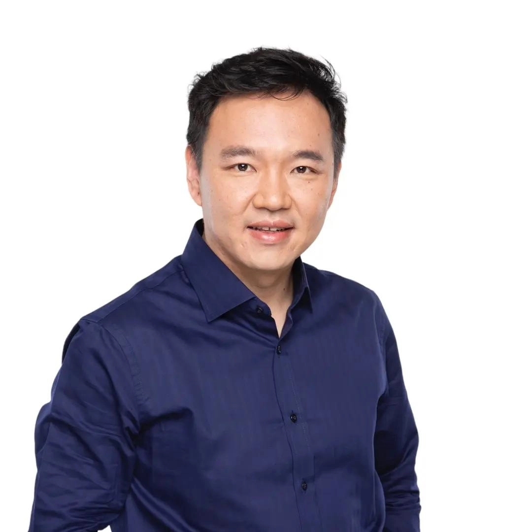 Man wearing a dark blue button-up shirt smiling against a white background.