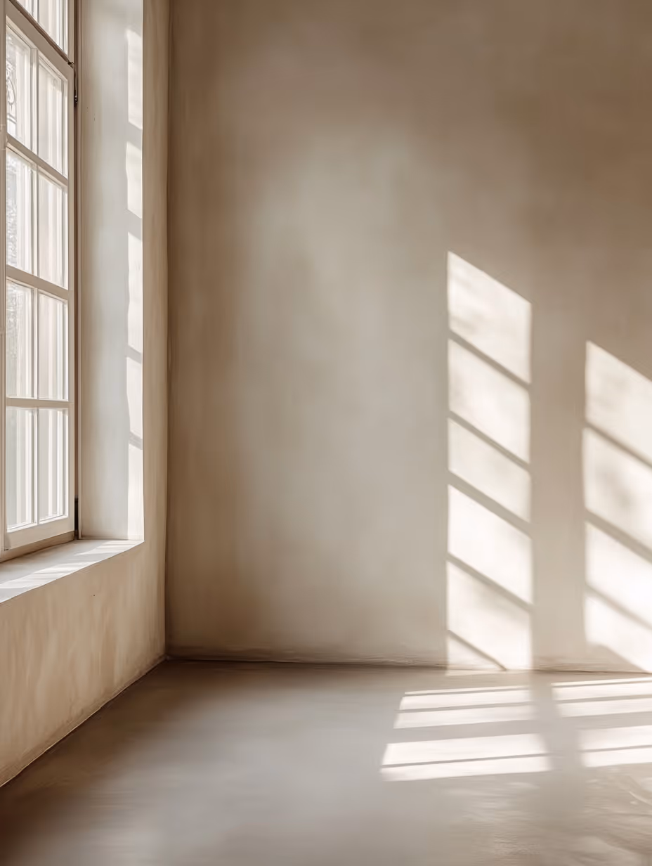 Sunlight casting window shadows on empty beige plastered room walls and floor.