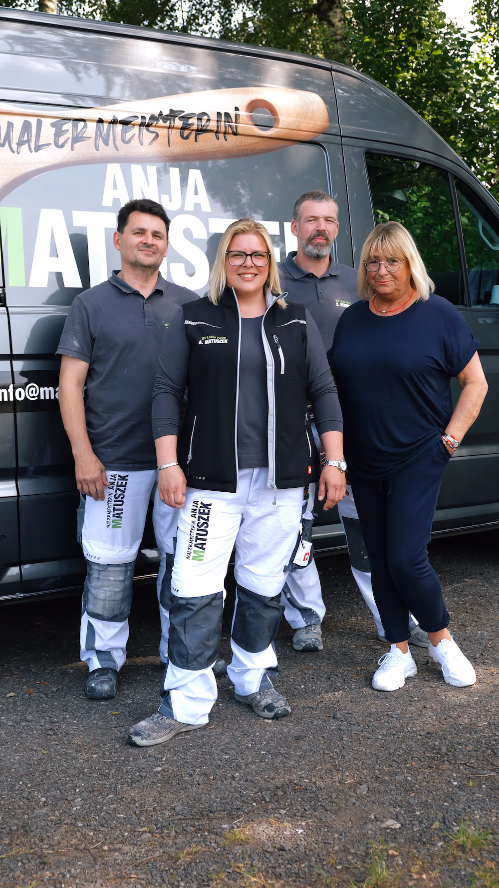 Four smiling people posing in front of a van with Anja Matuszek painting company branding.