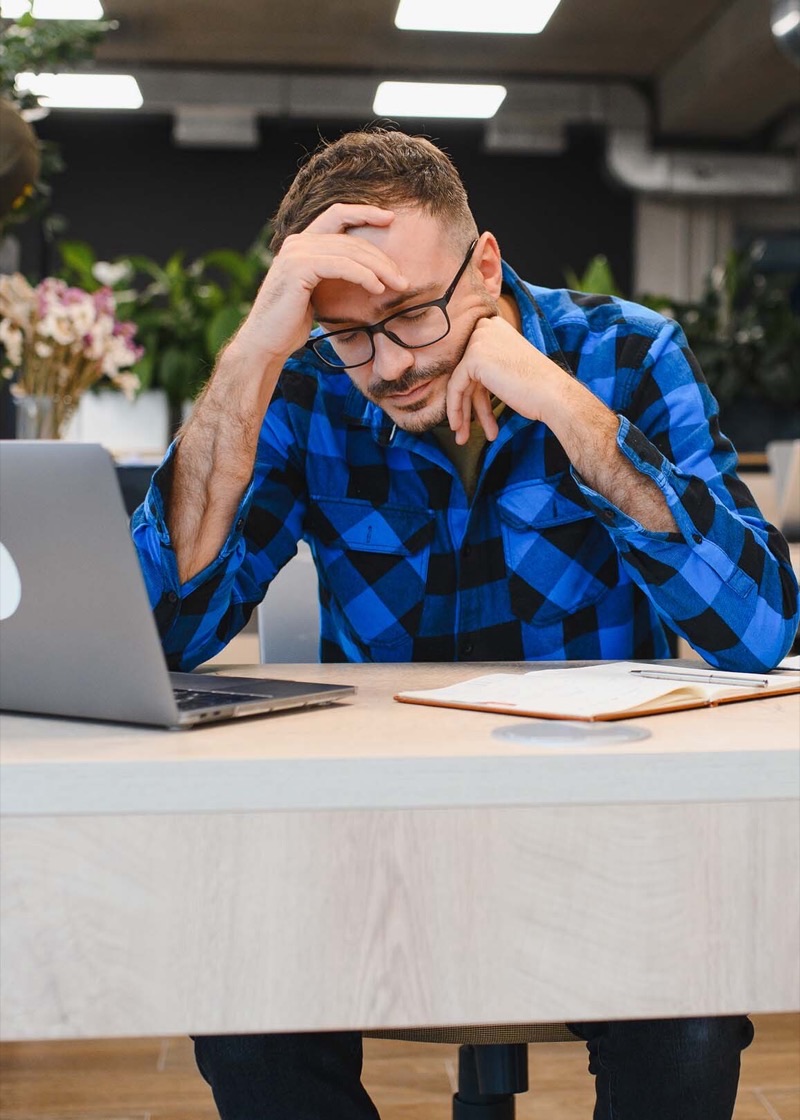 Stressed business owner working at a desk with a laptop.