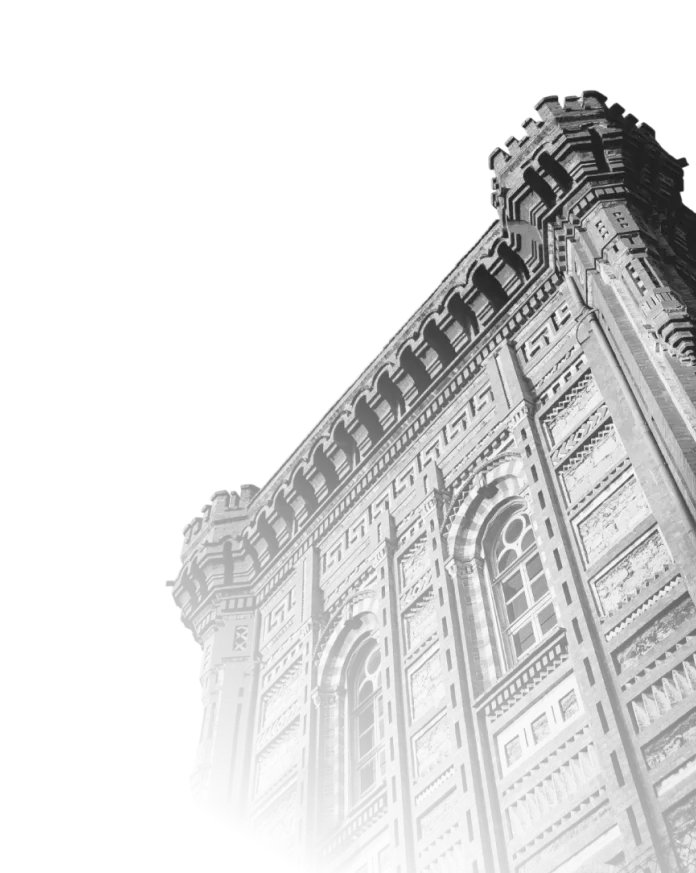 Black and white photo of an ornate historic building corner with arched windows and detailed brickwork.