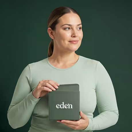 Woman in light green shirt holding a dark green box labeled Eden against a green background.
