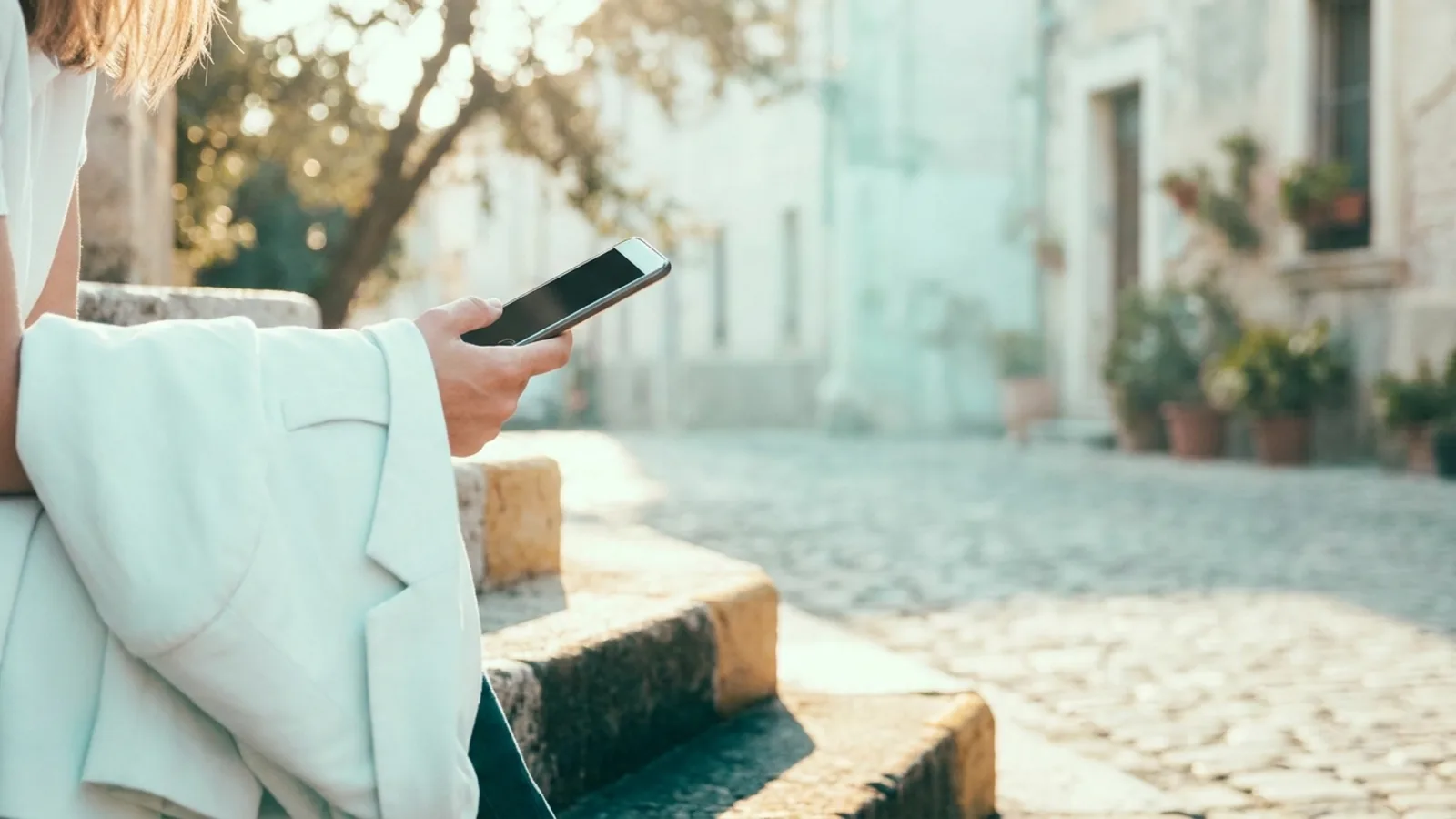 A person holding a phone on the steps outside after a therapy session, warm late afternoon light