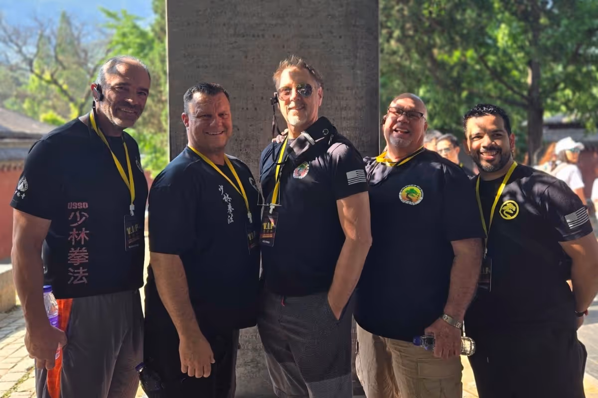 United Studios' leadership standing in front of their stone monument at the Shaolin Temple