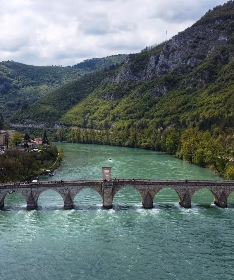 The historic Mehmed Pasa Sokolovic Bridge (Visegrad Bridge) spanning the green waters of the Drina River in Bosnia and Herzegovina.