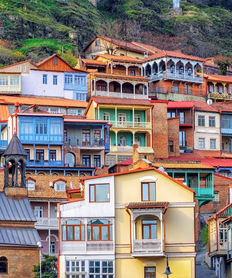 Vibrant, colorful traditional carved wooden balconies on houses stacked up the hillside in Old Tbilisi, Georgia.