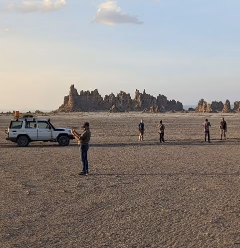 An image of a group of adventure travelers on an desert expedition taking images of the breathtaking landscape. 