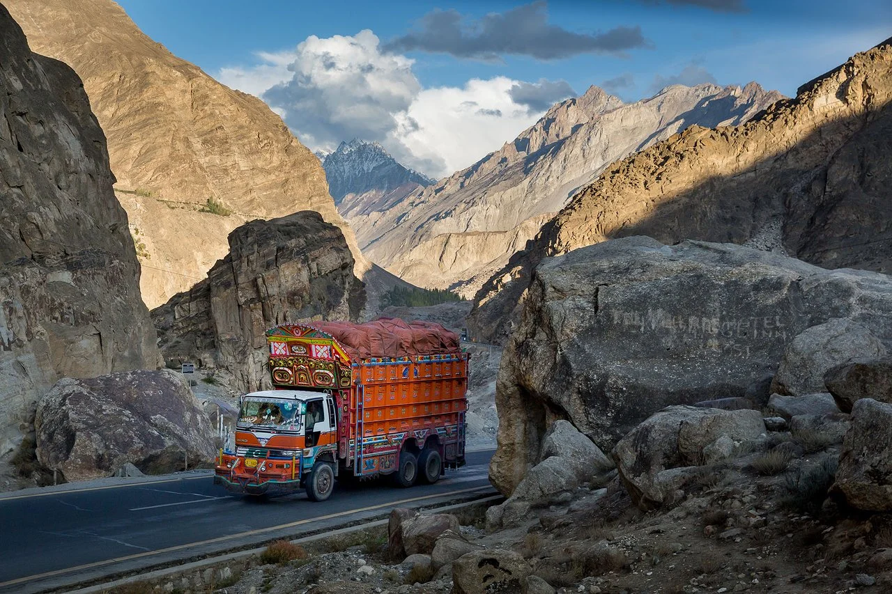 Decorated Pakistani truck drives along the Karakoram Highway through rocky gorges and peaks.