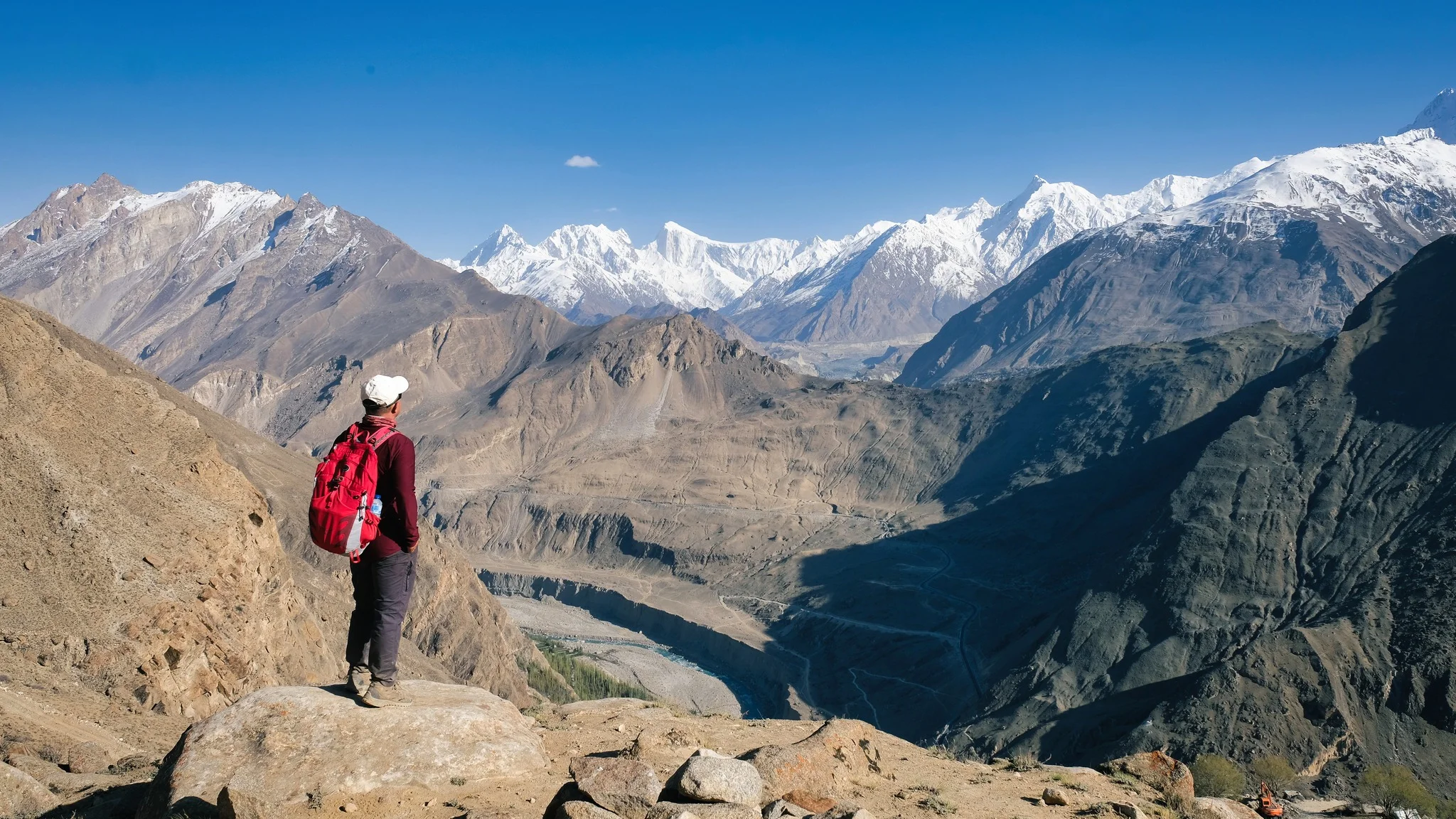 Hiker at Duiker viewpoint overlooks Hunza’s dramatic valley and snow-covered mountain range.