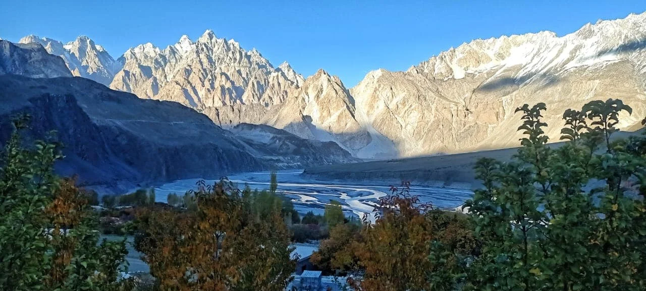 Morning light bathes Passu Valley’s iconic peaks and braided river system through autumn leaves.