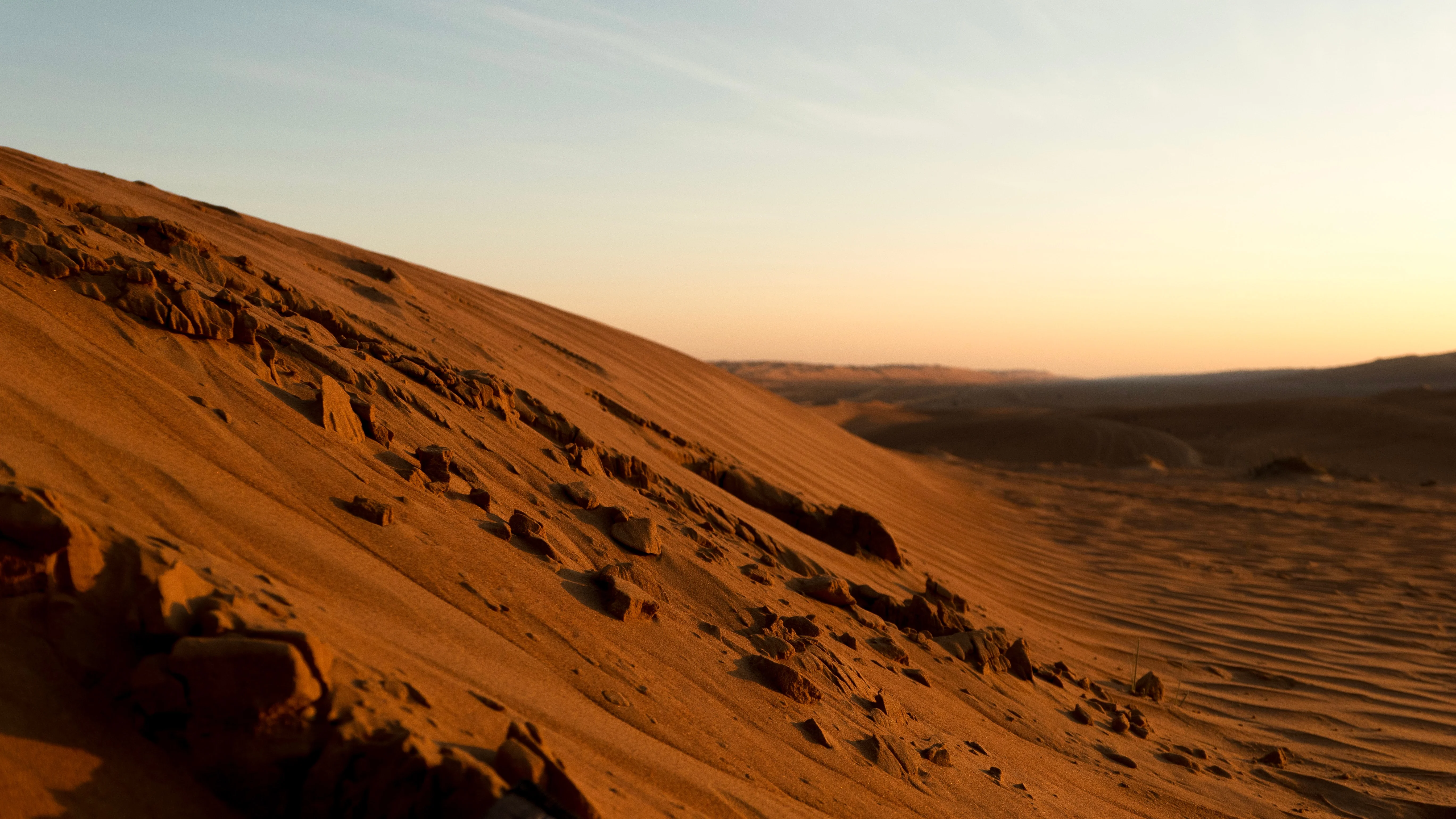 Rocky sand dunes at sunset in Wahiba Sands explored on an Oman tour.