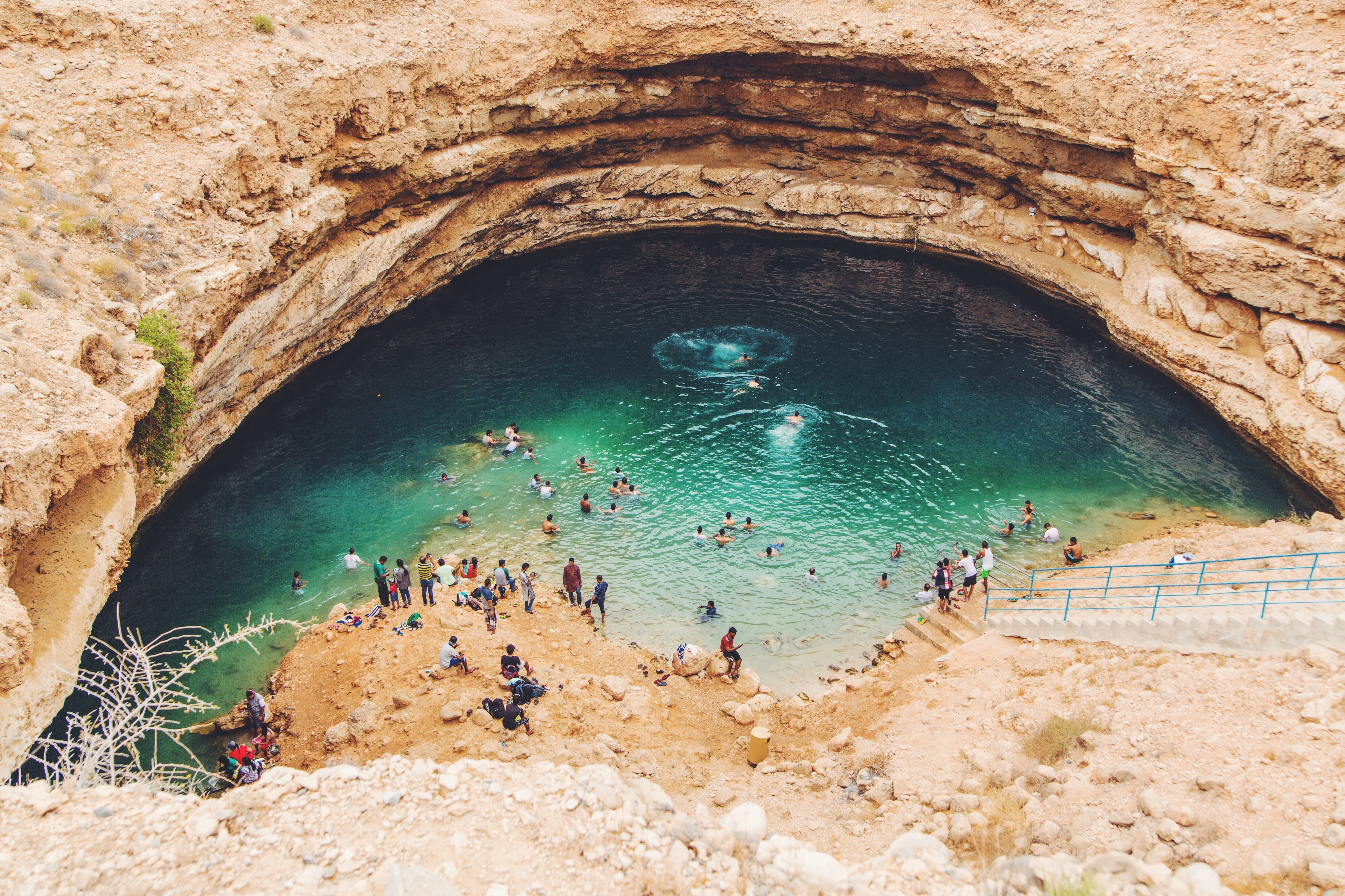 People swimming in turquoise Bimmah Sinkhole on an Oman tour adventure.
