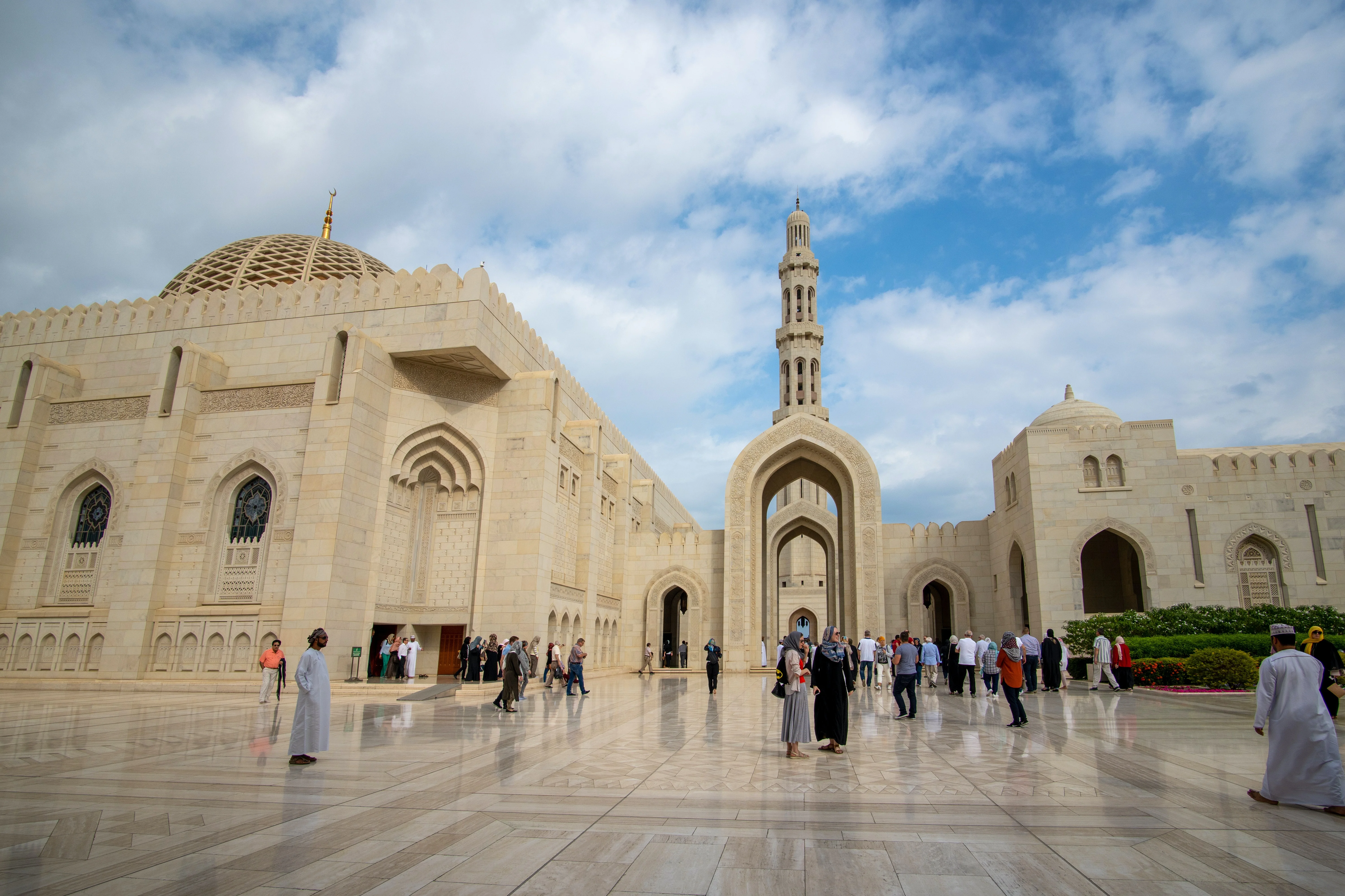 Visitors exploring courtyard of Sultan Qaboos Grand Mosque on an Oman tour.