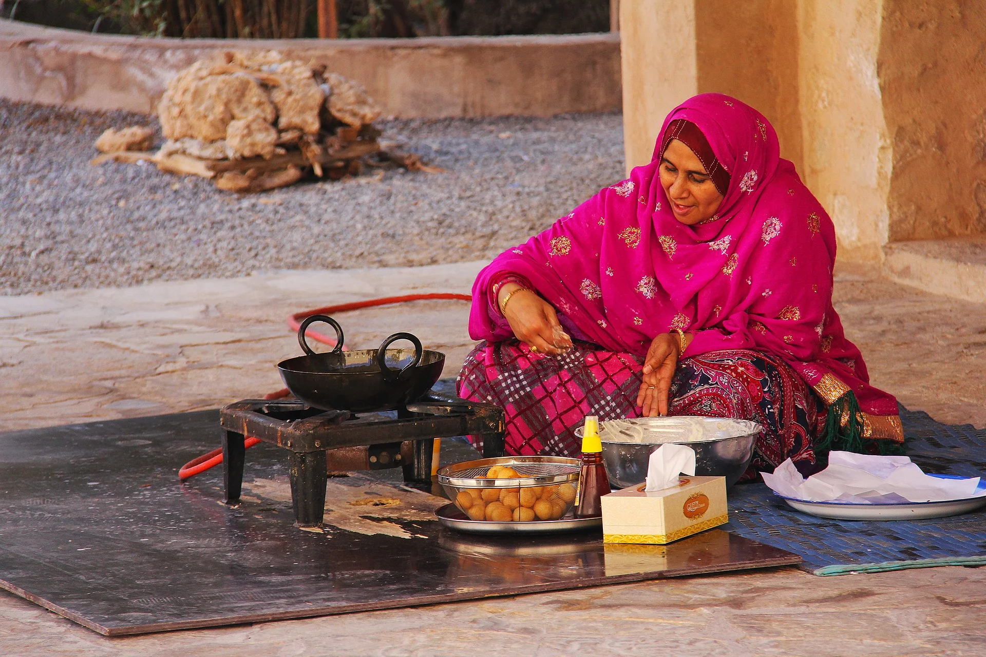 Omani woman cooking traditional sweets during a cultural stop on an Oman tour.