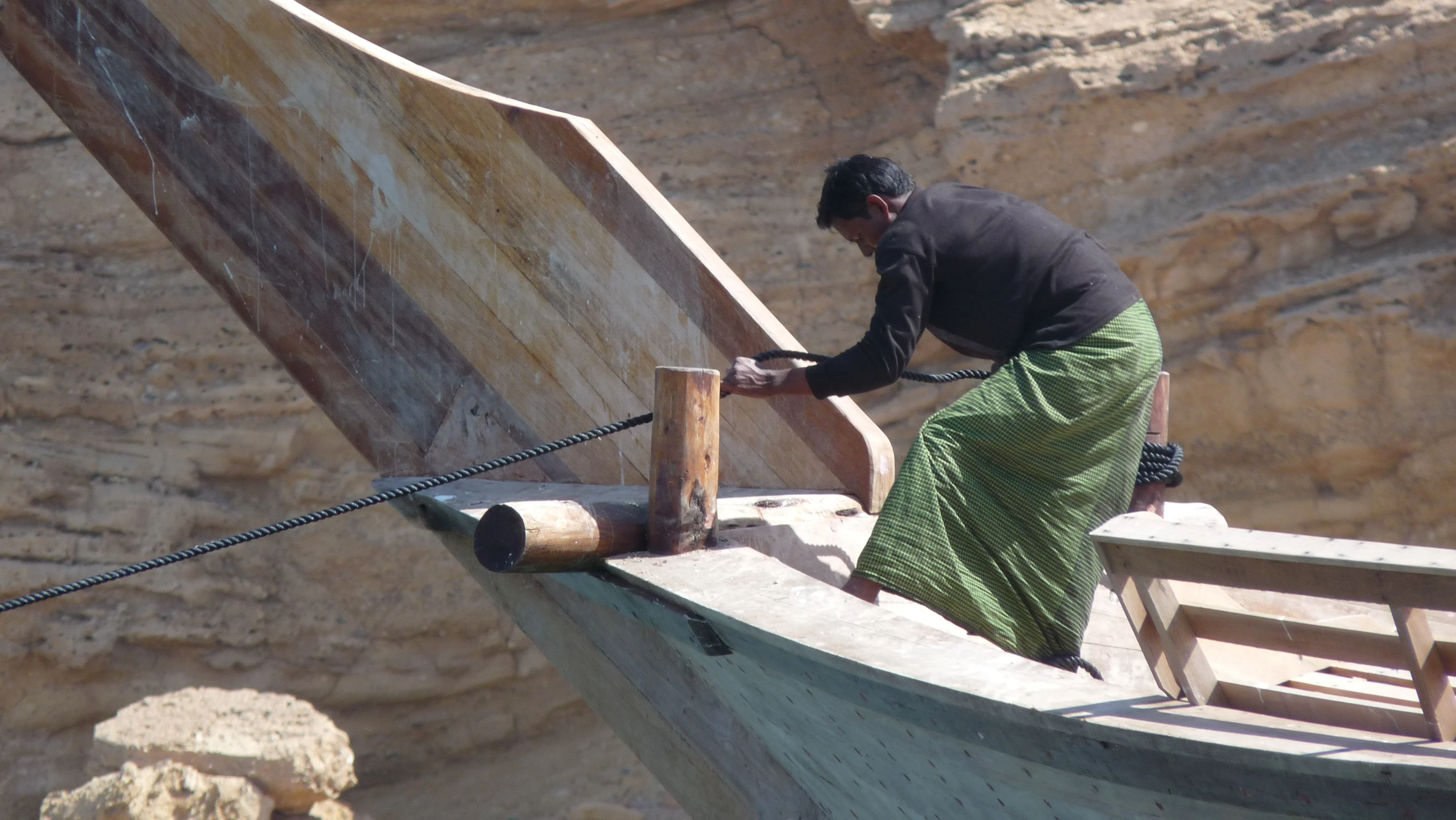 Local man working on traditional dhow boat captured on a coastal Oman tour.