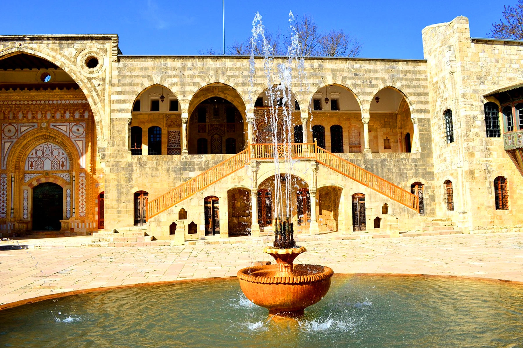 Fountain in the courtyard of Beiteddine Palace with arched hallways and detailed stonework.