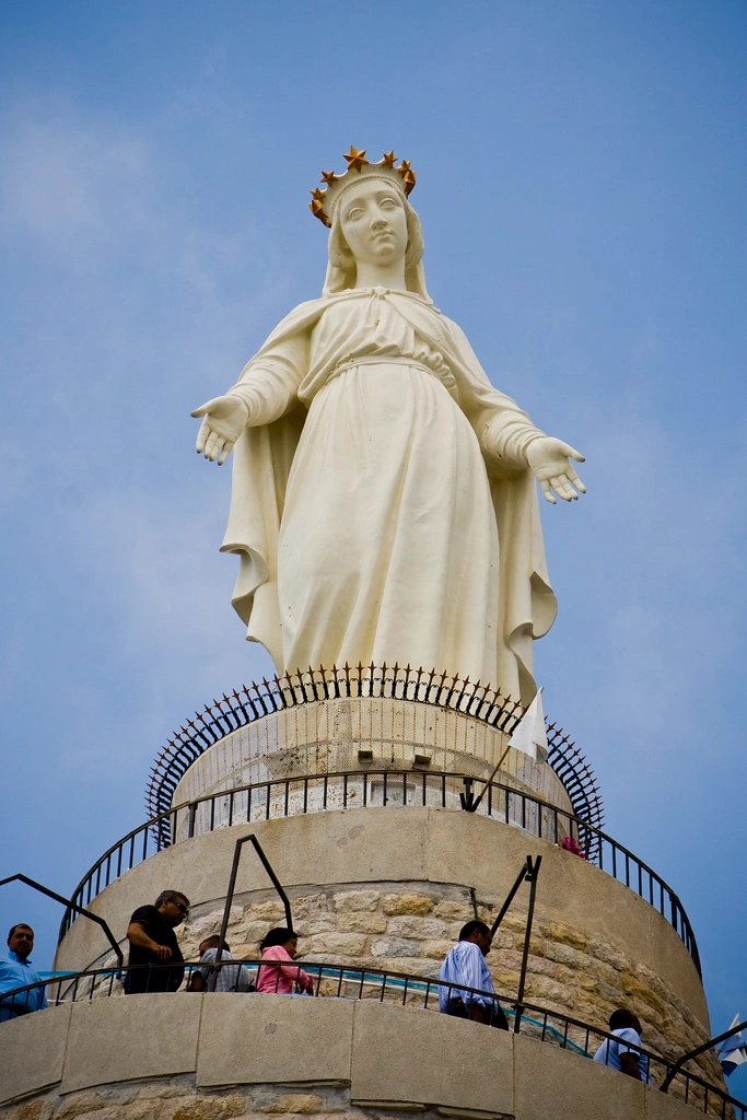 Statue of Our Lady of Lebanon in Harissa with visitors walking around its base.