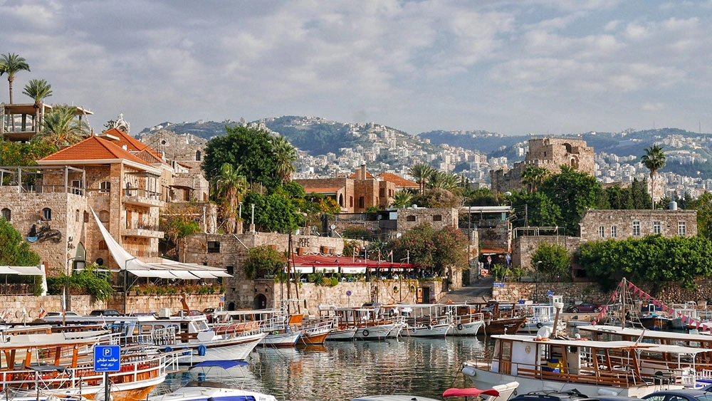 Boats docked at the picturesque Byblos harbor with historic stone buildings in view.