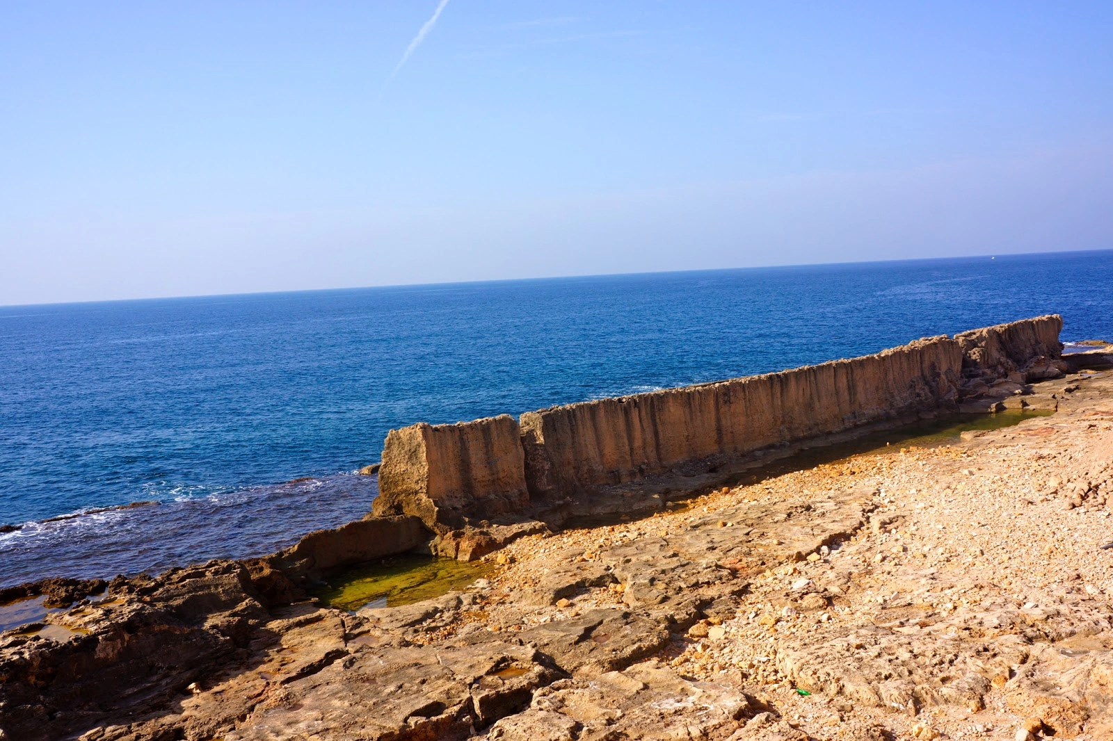 Rocky shoreline and coastal rock wall meeting the Mediterranean Sea in Ras El Metn.