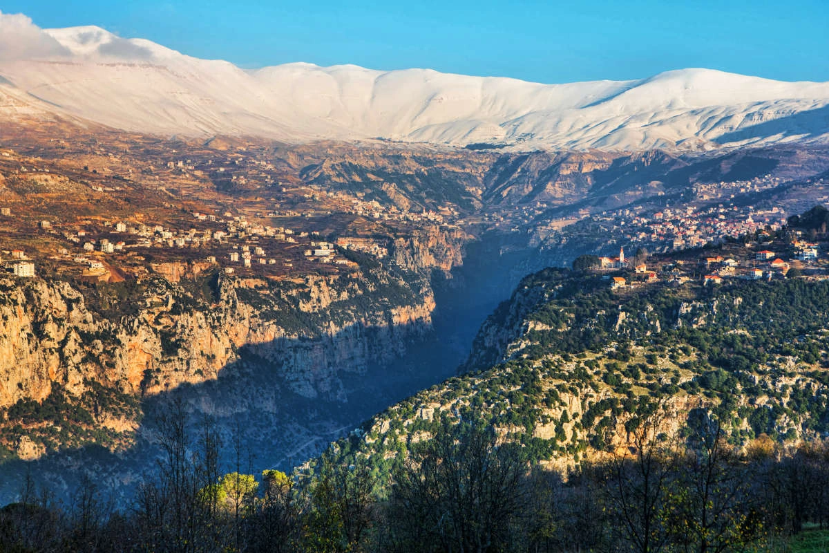 Snow-covered peaks and deep gorge of Qadisha Valley surrounded by mountain villages.