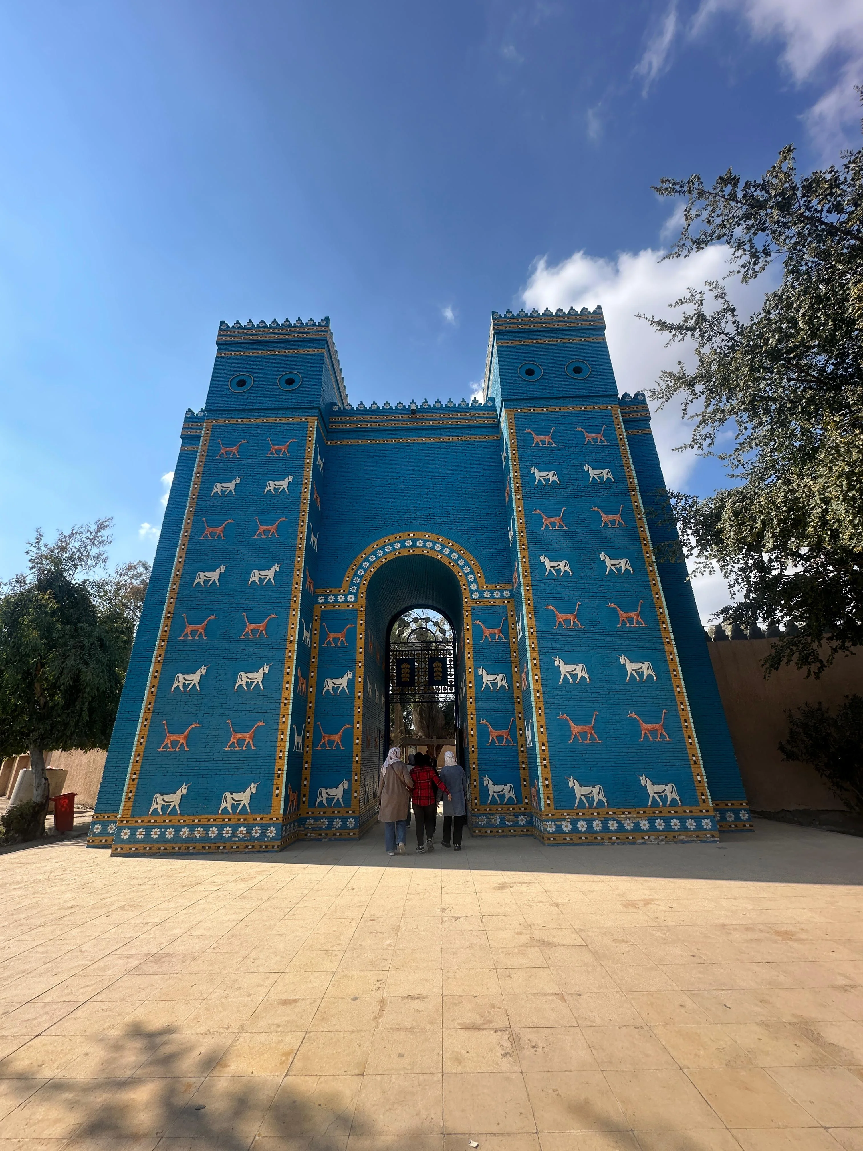 Replica of Ishtar Gate in Babylon, Iraq with blue bricks and mythical animal reliefs under clear sky